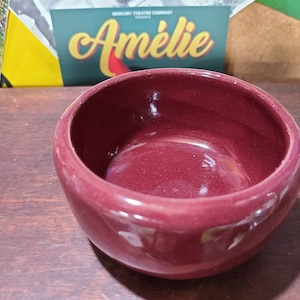 May include: A deep red ceramic bowl with a smooth, glossy finish. The bowl is empty and ready to be filled.