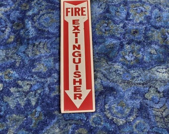 May include: White and red sign with an arrow pointing down. The sign reads "FIRE EXTINGUISHER".