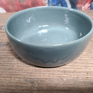 May include: A light blue ceramic bowl with a smooth, glossy finish. The bowl is empty and appears to be made of stoneware.