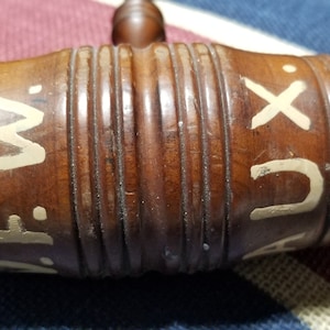 May include: A wooden gavel with white painted letters that read "A.F.W. AUX" on the side. The gavel has a brown finish and is made of wood.
