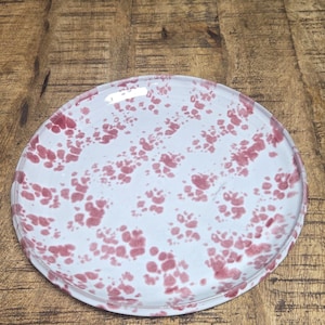 May include: A white ceramic mug with a black handle and the text "But First, Coffee" in a bold, black font. The mug is set against a blurred background, suggesting a cozy setting.