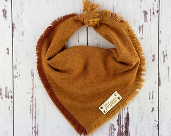 May include: A brown and orange dog bandana with a frayed edge and a small leather tag that says "Kitsune Creations".