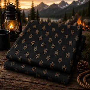 May include: A folded piece of black fabric featuring a repeating geometric pattern in gold. The textile displays a series of small, stylized, symmetrical shapes arranged in a grid across the dark surface, creating a consistent visual texture.