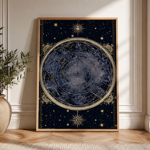 Może przedstawiać: Prostokątny wydruk ścienny przedstawiający ciemnogranatową mapę nieba ze złotymi gwiazdozbiorami i znakami zodiaku ułożonymi w okrąg. Wzór zawiera centralnie umieszczoną twarz słońca, złote zdobienia w rogach oraz różę wiatrów.