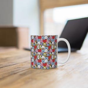 Puede incluir: Una taza de cerámica blanca con un patrón repetitivo de personajes de dibujos animados coloridos, incluyendo corazones rojos, koalas azules, perros amarillos, conejos rosas y alpacas blancas. El diseño cubre toda la superficie exterior cilíndrica.