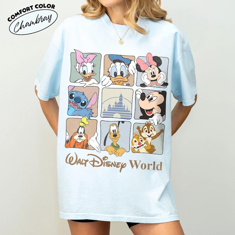 Puede incluir: Una camiseta azul claro con una cuadr&iacute;cula de nueve cuadrados que muestra varios personajes de Disney, incluyendo a Daisy, el Pato Donald, Minnie Mouse, Stitch, Mickey Mouse, Goofy, Pluto, Chip y Chop, y un castillo. El texto Walt Disney World aparece debajo.