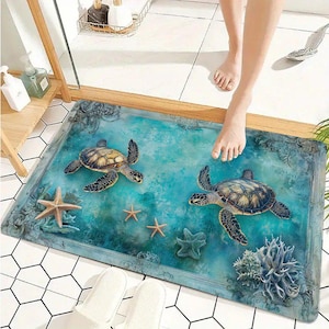 Puede incluir: Una alfombrilla de baño rectangular con un estampado de alta definición de dos tortugas marinas nadando en agua turquesa. El diseño incluye tres estrellas de mar y una formación de coral, enmarcado por un borde ornamental de estilo antiguo.