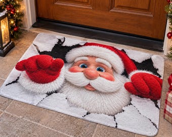 May include: A rectangular doormat featuring a 3D-style graphic of Santa Claus appearing to break through a white, cracked surface. Santa has a red hat, white beard, and red mittens, with blue eyes and a pink nose visible on the mat.