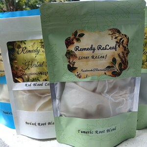 May include: Three stand-up pouches containing herbal blends. The front pouch is light green with a label reading Remedy ReLeaf Liver ReLeaf and Tumeric Root Blend. The middle pouch is white with a label reading Remedy ReLeaf Herbal Blend and Burdock Root Blend. The back pouch is blue.