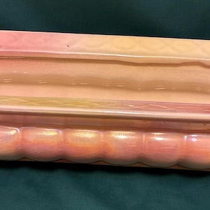 May include: A rectangular ceramic planter featuring an iridescent finish with a gradient of soft pink and yellow hues. The exterior base has a rounded, scalloped texture, while the wide rim displays a subtle, embossed diamond pattern.