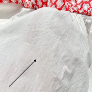 Peut inclure: Tissu de coton blanc avec une petite tache brune. Le tissu est froiss&eacute; et a un l&eacute;ger brillant.