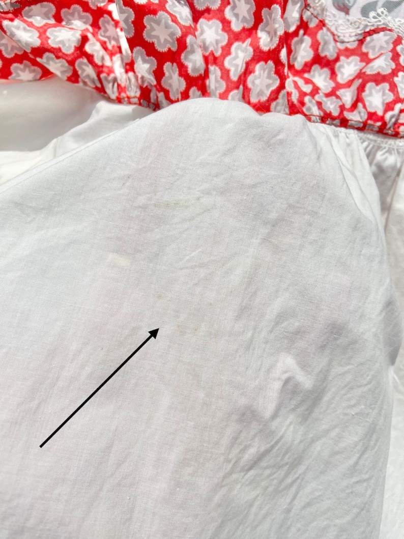 Peut inclure: Tissu de coton blanc avec une petite tache brune. Le tissu est froiss&eacute; et a un l&eacute;ger brillant.