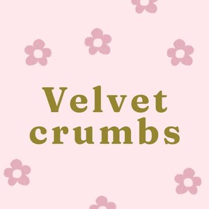 Puede incluir: Un fondo rosa claro con un patrón repetitivo de pequeñas flores malvas de cinco pétalos. Centrado en la imagen está el texto "Velvet crumbs" escrito en una fuente serif negrita de color verde oliva oscuro, posicionado horizontalmente.