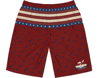 May include: Red shorts featuring a waistband with horizontal white stripes and blue bands adorned with white stars. The lower portion displays a dark blue pattern of palm trees and birds, with a single hibiscus flower graphic in the bottom right corner.