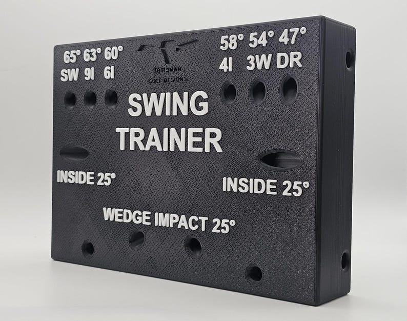 May include: A black rectangular golf swing trainer with white text and markings. The device features labels including SW, 6I, 4I, 3W, DR, and various degree angles. The center displays the words SWING TRAINER and WEDGE IMPACT 25 degrees.