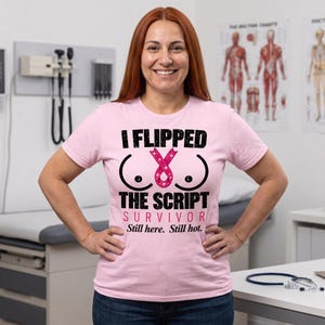 May include: A light pink short-sleeve t-shirt featuring black text that reads I FLIPPED THE SCRIPT, a glittery pink breast cancer awareness ribbon, and the text SURVIVOR Still here. Still hot. in pink and black lettering on the front.