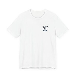 May include: A white short-sleeved t-shirt featuring a small graphic on the upper left chest. The graphic displays the text SH CO in bold letters, positioned above two crossed oars and a small figure in a rowing boat, rendered in dark blue and black.