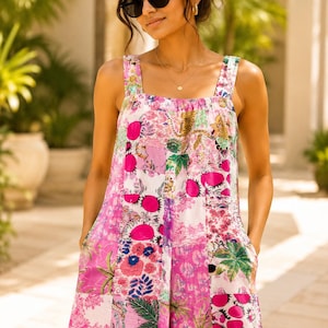Può includere: Una tuta senza maniche con un design patchwork caratterizzato da vari motivi nei toni del rosa acceso, bianco e verde. Il capo presenta spalline larghe, uno scollo quadrato e tasche laterali, con motivi raffiguranti piante e animali tropicali.