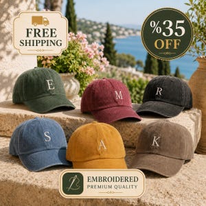 May include: Six baseball caps in various colors including dark green, maroon, charcoal, blue, mustard yellow, and brown. Each cap features a single embroidered letter on the front panel, specifically E, M, R, S, A, and K, in a white serif font.