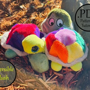May include: Two plush turtle toys featuring multicolored shells with patches of red, purple, orange, yellow, and green fabric. The turtles have light green heads with dark eyes and white trim. Text on the image reads .PDF Pattern + Tutorial and Reversible Plush.