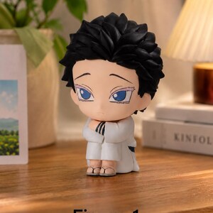 Puede incluir: Una peque&ntilde;a figura de un personaje con cabello negro puntiagudo y ojos azules, vistiendo un atuendo blanco. La figura est&aacute; arrodillada con los brazos cruzados. El texto "Figure 1" est&aacute; en la parte inferior.