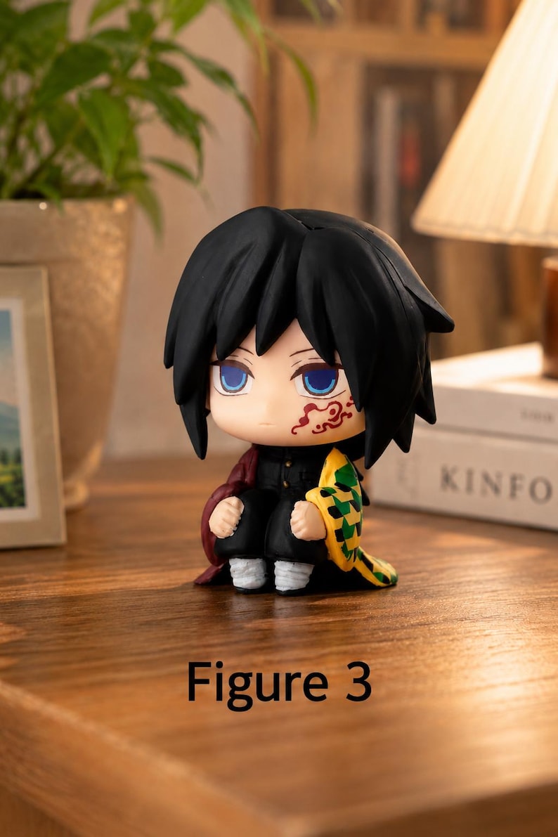 Puede incluir: Peque&ntilde;a figura de anime con cabello negro, ojos azules y una marca roja en la cara. La figura lleva un atuendo negro con una capa roja y sostiene un objeto amarillo y verde. El texto "Figure 3" est&aacute; en la parte inferior.
