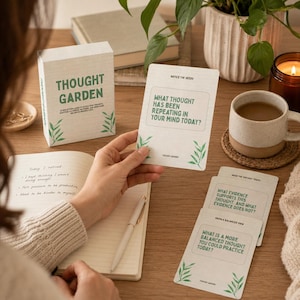 May include: A deck of Thought Garden reflection cards with green text and leaf illustrations. The box and cards feature prompts like What thought has been repeating in your mind today? and What evidence supports this thought? on off-white cardstock.