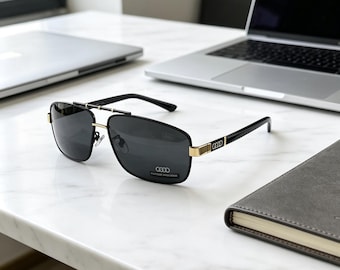 Occhiali da sole polarizzati rettangolari da uomo con logo Audi, disponibili in quattro colori di montatura, con protezione UV e confezione originale.