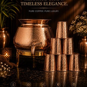 Op de afbeelding: Een koperen drankdispenser met een kraan en zes bijpassende koperen bekers. De dispenser en bekers hebben een gehamerde textuur. De afbeelding bevat de tekst "HERITAGE CRAFT. TIMELESS ELEGANCE."