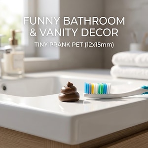May include: A brown, coiled prank object measuring 12x15mm, positioned next to a white toothbrush with multicolored bristles. The text "FUNNY BATHROOM & VANITY DECOR" and "TINY PRANK PET (12x15mm)" is displayed in white lettering above the objects.