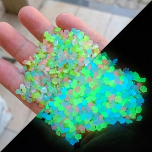 May include: A collection of small, irregular, translucent stones in shades of neon green, light blue, and soft pink. The stones are divided into two distinct visual states: one side appears as matte, pastel-colored pebbles, while the other side glows.