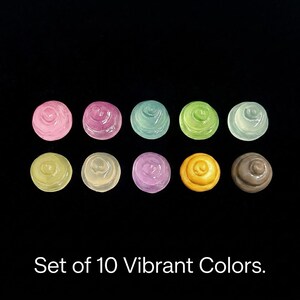 May include: A set of ten small, round, swirl-topped cabochons in various colors including pink, magenta, light blue, lime green, pale green, yellow, cream, purple, orange, and brown. The text "Set of 10 Vibrant Colors." is printed below the items.