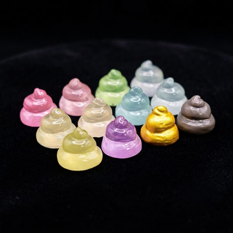 May include: A collection of twelve small, swirl-shaped figurines in various colors including pink, green, blue, yellow, purple, gold, and brown. Each figurine features a smooth, glossy finish and a rounded, stacked design with a pointed top.