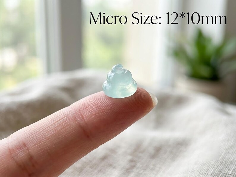 May include: A small, translucent, pale green carved figurine shaped like a coiled pile, measuring 12 by 10 millimeters. The object has a smooth, polished surface and a rounded, tiered form, displayed clearly against a neutral, soft-textured background.
