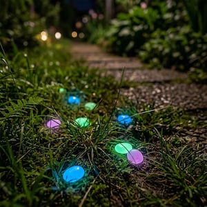 May include: A collection of small, smooth, oval-shaped decorative stones scattered throughout green grass. These stones emit a soft, glowing light in various colors, including blue, green, and purple, creating a luminous effect in the dark.