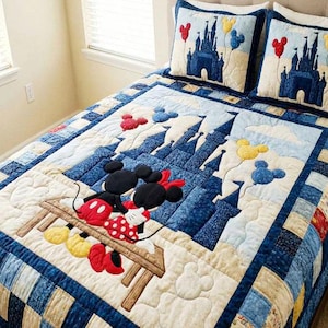 May include: A quilted bedspread and two matching pillowcases featuring a Disney theme. The quilt showcases Mickey and Minnie Mouse, a castle, and Mickey Mouse-shaped balloons in shades of blue, red, yellow, and white.