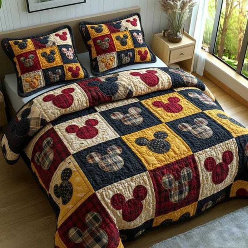 May include: A patchwork quilt and two pillow shams featuring a Mickey Mouse design. The bedding set has a color scheme of red, yellow, navy, and cream. The quilt and pillow shams are square-patterned with Mickey Mouse head shapes.