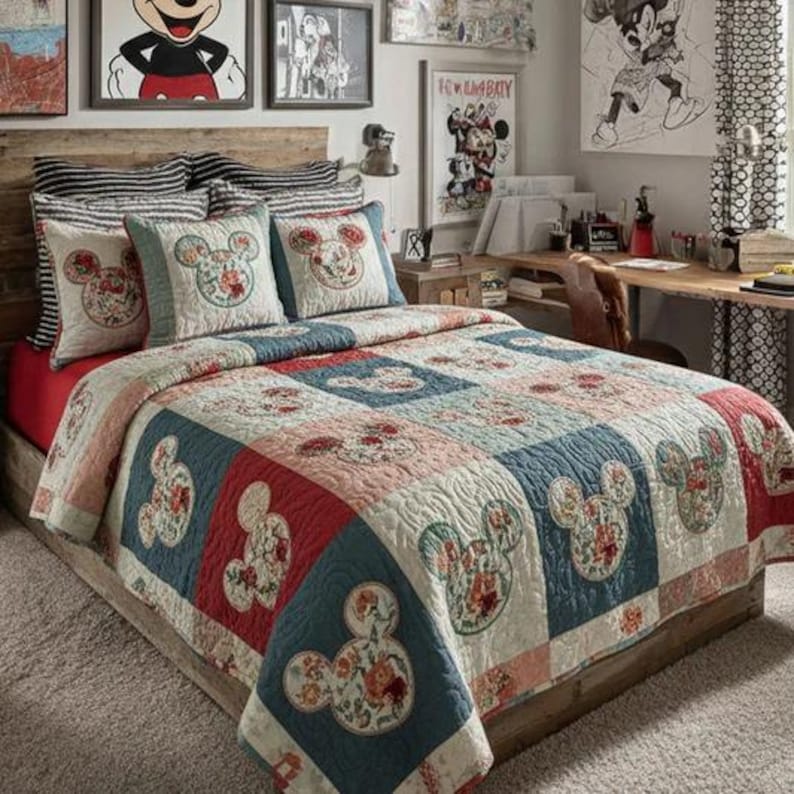 May include: A bed featuring a patchwork quilt and matching pillows with a floral Mickey Mouse design. The quilt has red, blue, and cream squares. The pillows have a blue border.