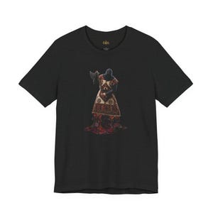 May include: A black short-sleeved t-shirt featuring a graphic print of a hooded figure wearing a patterned tunic and holding an axe. The figure appears to be standing in a pool of red liquid. The brand name Cultz is printed in gold inside the neck.