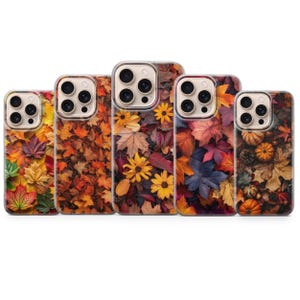May include: Five smartphone cases arranged in a row, each featuring a distinct autumn-themed design. The patterns display a variety of colorful fallen leaves, yellow sunflowers, and small pumpkins in shades of orange, red, brown, and deep purple.