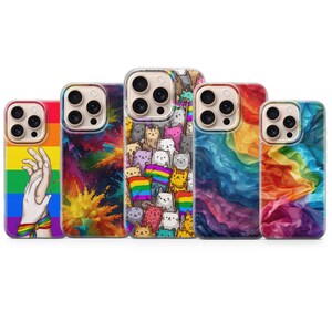 以下が含まれることがあります： 鮮やかなデザインのスマートフォンケース5点：虹色の旗の上に重なる2つの手、カラフルな粉末の爆発、虹色の旗を持つ猫の群れ、渦巻く虹色の煙、そして虹色の布地がそれぞれ描かれています。