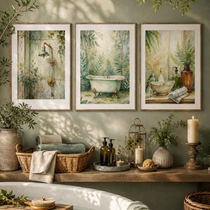 May include: Three framed wall art prints featuring watercolor illustrations of bathroom scenes. The left print shows a shower, the center print depicts a clawfoot bathtub, and the right print displays a washbasin with bottles and towels.