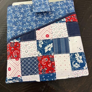 Puede incluir: Funda acolchada para fuente de horno, estilo patchwork, con diseños azules, rojos y blancos. El diseño incluye estampados florales, paisley y de lunares. La parte superior es azul con motivos de hojas blancas, y una pequeña pestaña asegura la funda.