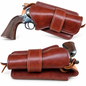 May include: A brown leather holster containing a revolver with a dark wood grip and a blue-toned metal frame. The holster features thick stitching, a wide retention strap across the center, and a smooth, polished finish on the exterior surface.