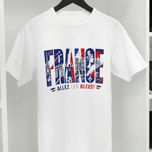 Puede incluir: Una camiseta blanca de manga corta con un estampado gr&aacute;fico de la palabra FRANCE en rojo, blanco y azul. Las letras contienen ilustraciones de la Torre Eiffel, un jugador de f&uacute;tbol y monumentos. Debajo del gr&aacute;fico aparece el texto ALLEZ LES BLEUS!