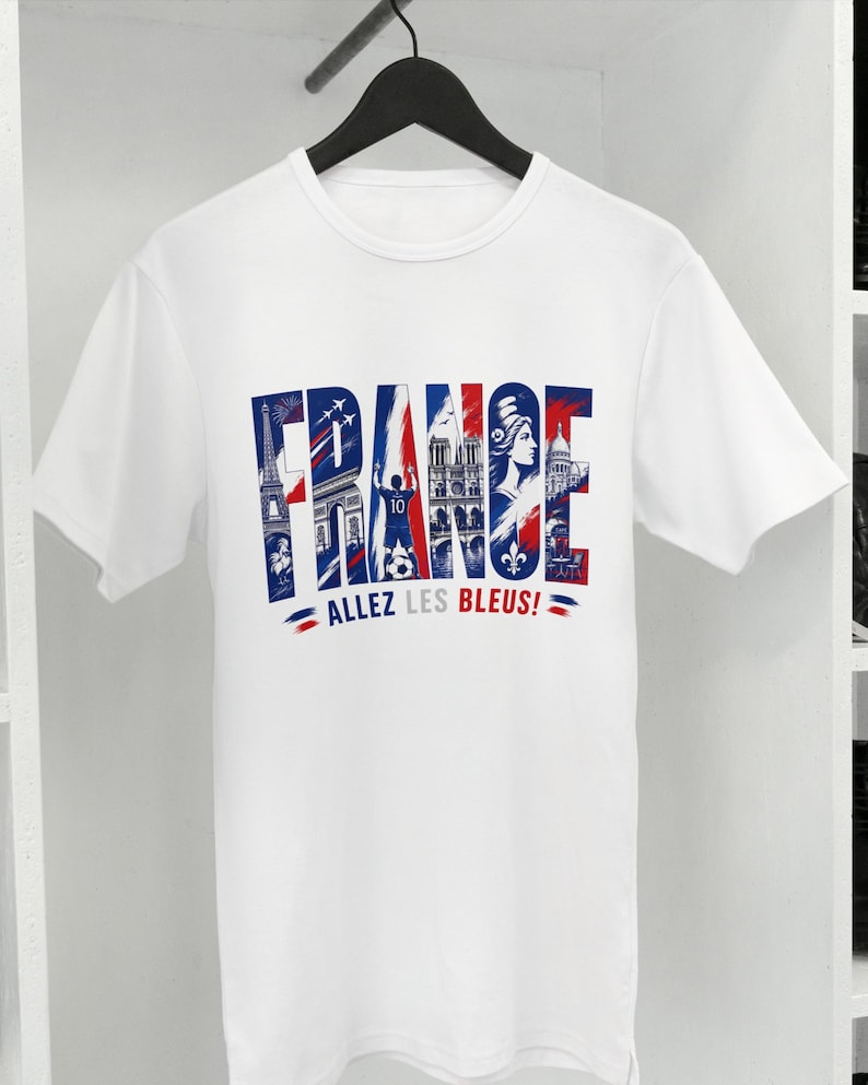 Puede incluir: Una camiseta blanca de manga corta con un estampado gr&aacute;fico de la palabra FRANCE en rojo, blanco y azul. Las letras contienen ilustraciones de la Torre Eiffel, un jugador de f&uacute;tbol y monumentos. Debajo del gr&aacute;fico aparece el texto ALLEZ LES BLEUS!