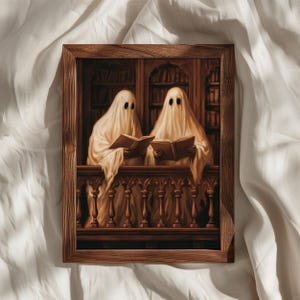 Puede incluir: Una impresión artística enmarcada que muestra dos figuras cubiertas con sábanas blancas, parecidas a fantasmas, de pie en un balcón de madera y leyendo libros abiertos. El fondo muestra una biblioteca oscura con estantes llenos de libros.
