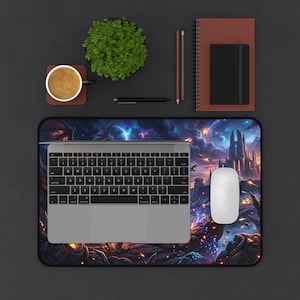 Può includere: Un mouse, una tastiera e un laptop sono su un tappetino per mouse a tema fantasy con un castello e un cielo colorato. Una tazza di caffè, una pianta, un taccuino e delle penne sono anche sulla superficie scura.