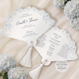 May include: Two fan-shaped wedding programs made of white cardstock with scalloped edges and blue floral line art. Each features a white tassel attached at the base. The text includes names, date, location, ceremony order, wedding party, and timeline.