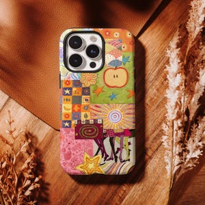 Op de afbeelding: Een smartphonehoesje met een kleurrijk patchworkontwerp met diverse illustraties, waaronder een appel, sterren, bloemen, een spiraal en een zonnestraalpatroon. Het hoesje heeft een zwarte camera-uitsparing en een veelkleurige collage van geometrische vormen.